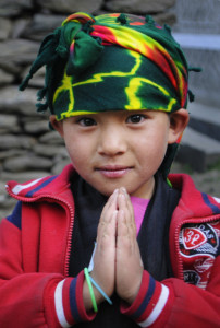 Caption: Sangmo, a Nepalese girl, makes the classic greeting sign, namaste.  Her well-deserved nickname is “Buta Maya” which means “sweet little thing.” Sangmo and her family came to the clinic where Ken Harvey volunteered in Nepal.  The wrap on her head, while in nontraditional colors, tells a bit of her heritage. Harvey will speak and show his photos of Nepal at the Nashua Public Library on January 7 at 7 p.m. Photo credit: Ken Harvey