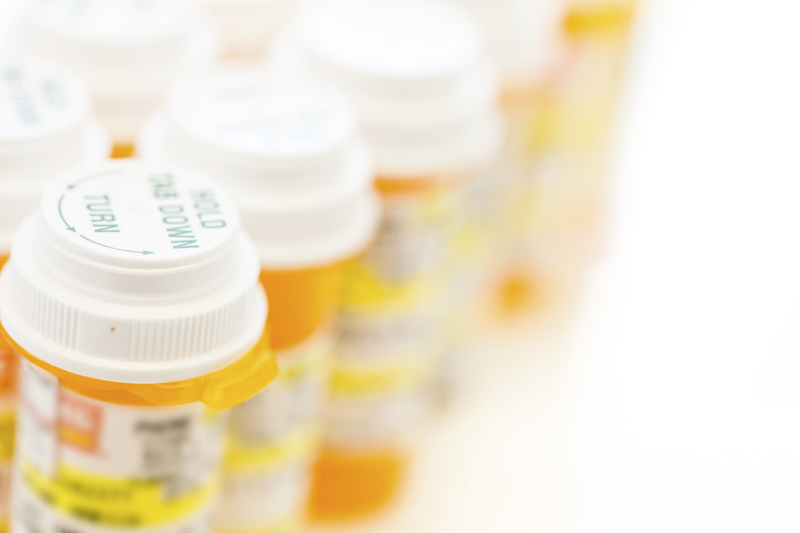 Prescription pills in yellow bottles on a white background.